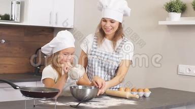 家庭<strong>合作愉快</strong>。 穿围裙的小女孩在碗里洒面粉做面团